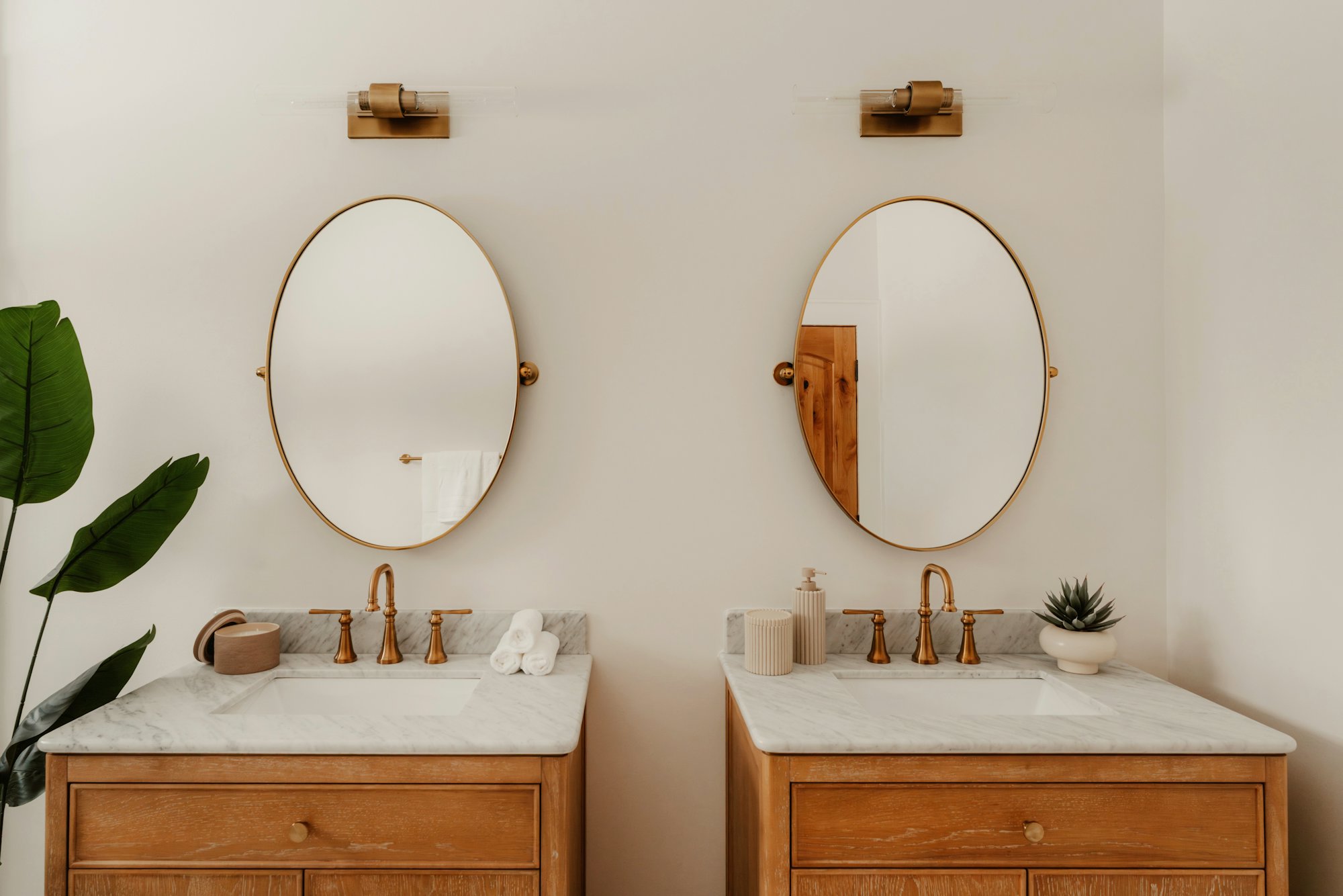 Calm bathroom with twin oak vanities, marble countertops and brass taps