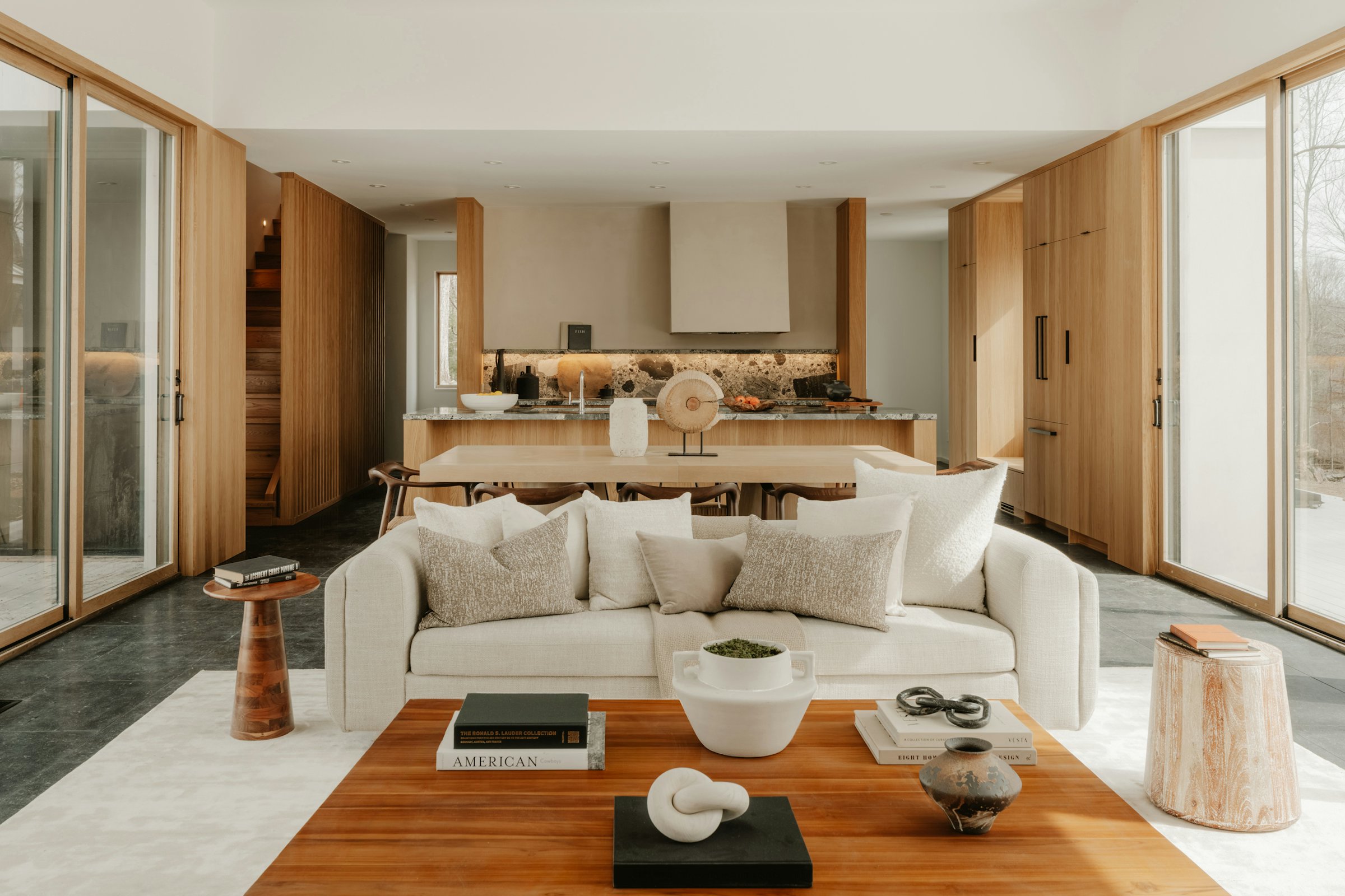 Bright open-plan living room with a cream sofa, oak-panelled walls and a stone kitchen island beyond